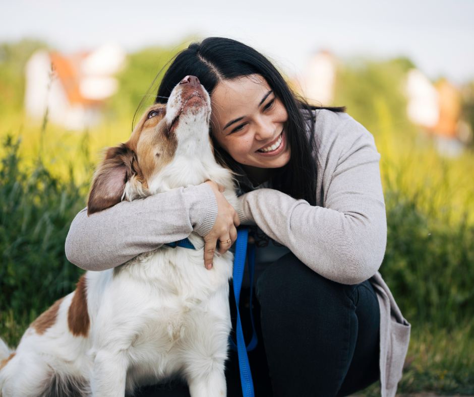 Woman hugging her dog outdoors, both looking happy and affectionate together.